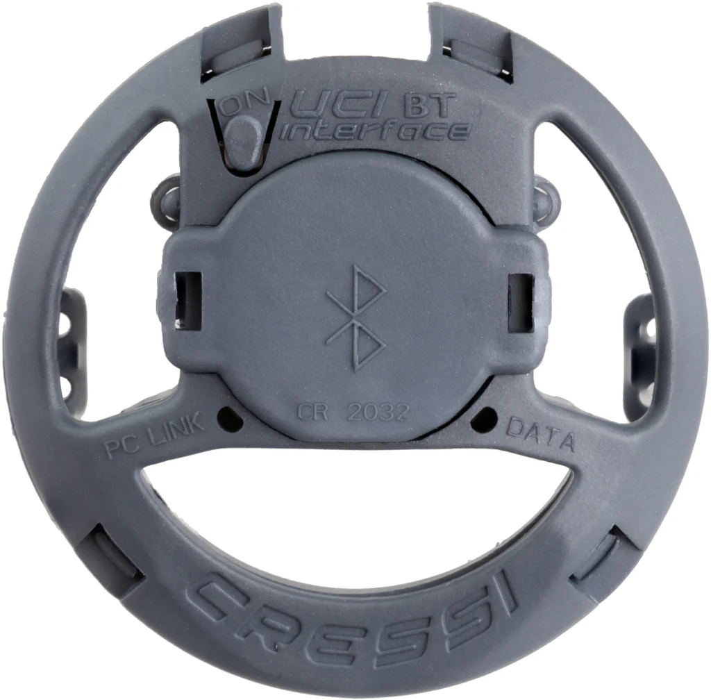 Ein Smartphone zeigt die Cressi Tauch-App mit einem grafischen Tiefenprofil, daneben liegt das aktive Bluetooth Interface